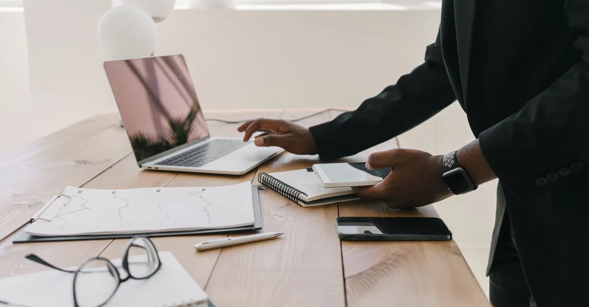 Espace de travail professionnel avec un ordinateur portable, des documents et des fournitures de bureau sur une table en bois.