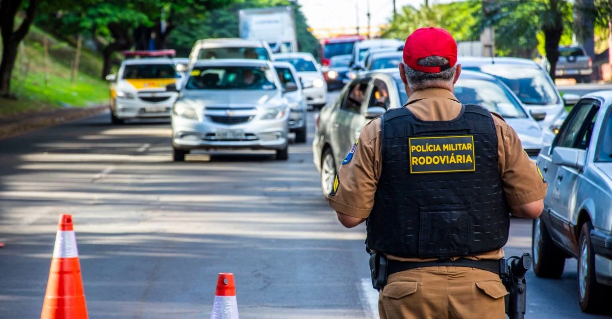 Agent de police dirigeant la circulation à Londrina, Brésil, avec des voitures et des cônes sur une rue animée.