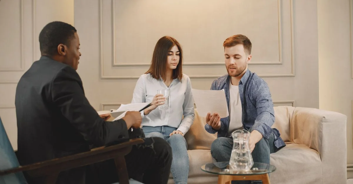 Thérapeute conseillant un couple avec des documents dans un cadre de bureau contemporain.