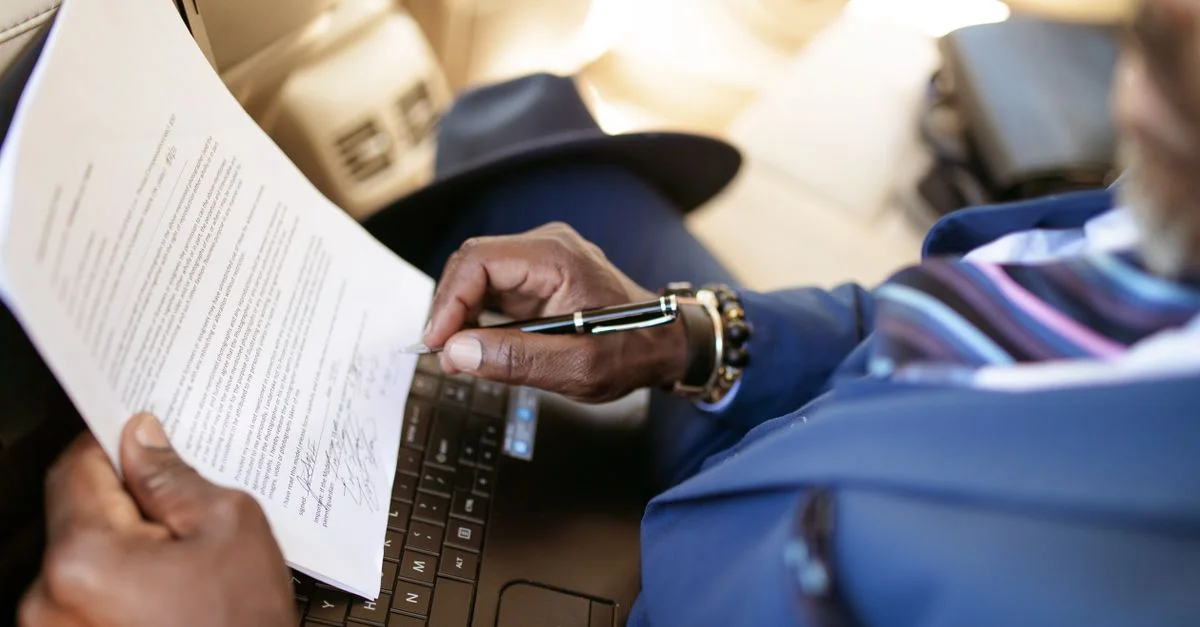 Gros plan sur un professionnel en tenue bleue révisant un document sur un ordinateur portable, soulignant les installations de travail modernes.