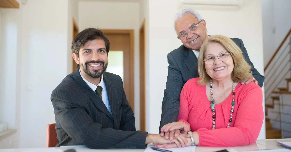 Couple senior souriant rencontrant un conseiller professionnel dans un cadre intérieur lumineux.